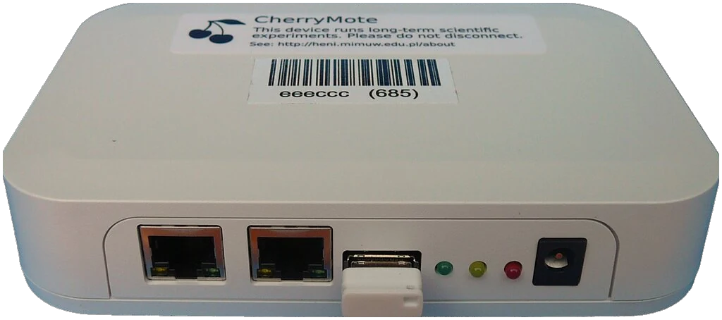A photo of CherryMote. It is a small white box with Ethernet ports, a USB port, LEDs and a power supply port in the front panel.